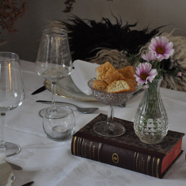 Ett dukat bord med en bok, skorpor och blomma.