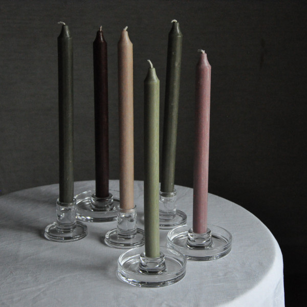 Ljusstakar i glas med färgade ljus på ett runt bord med vit duk.