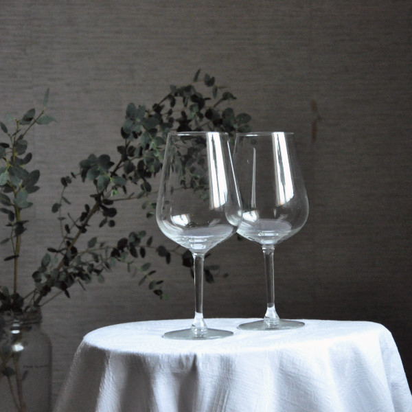 Två tomma vinglas på ett bord med vit duk.