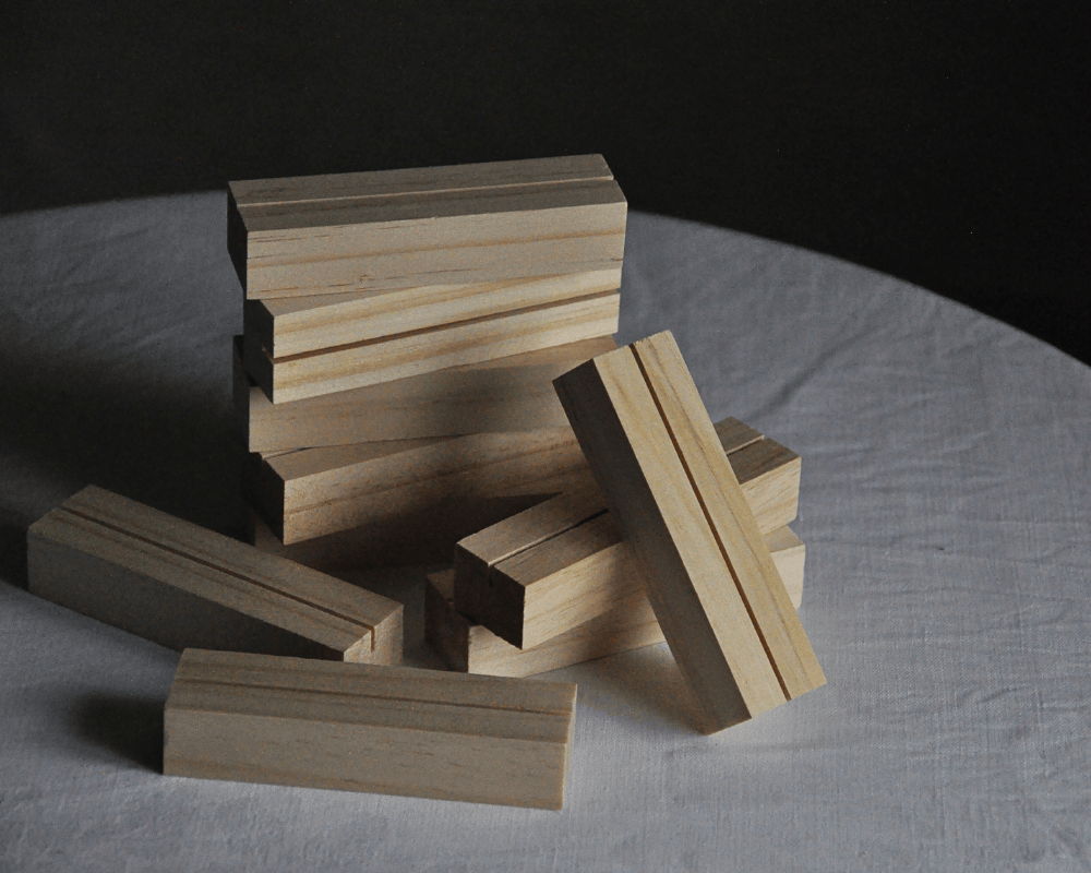 Skylthållare i ljust trä, de ligger i en hög.